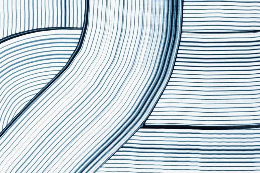 Abstract flowing curved lines in varying shades of blue on white background, creating a wave-like pattern.