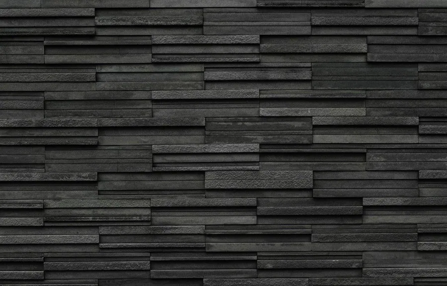 Staggered charcoal and grey brick tiles with varied surface textures creating a 3D wall effect