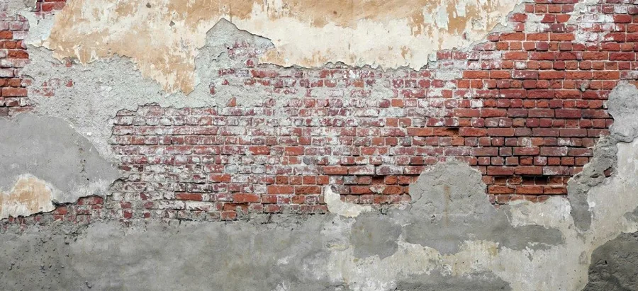 Weathered red brick wall with peeling white and grey plaster revealing aged texture layers