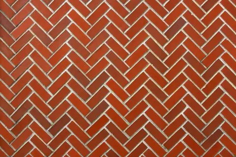 Repeating herringbone brick pattern in terracotta with grey mortar joints