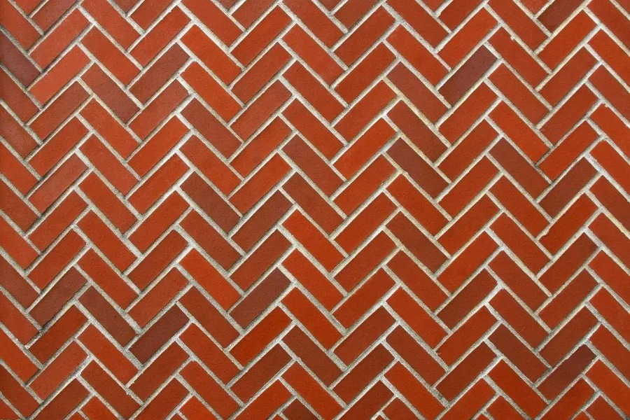 Repeating herringbone brick pattern in terracotta with grey mortar joints