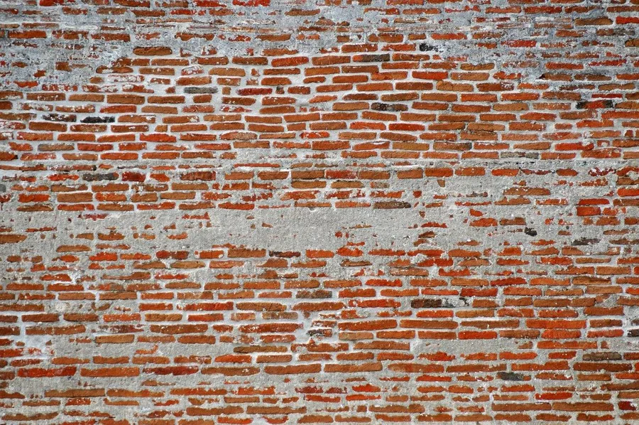 Distressed red brick wall with peeling white paint and weathered texture