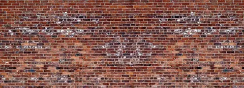 Close-up of aged red brick wall with white paint patches and natural wear patterns
