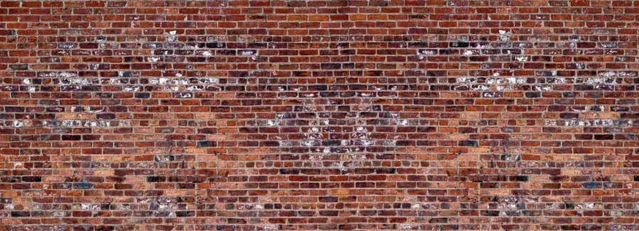 Close-up of aged red brick wall with white paint patches and natural wear patterns