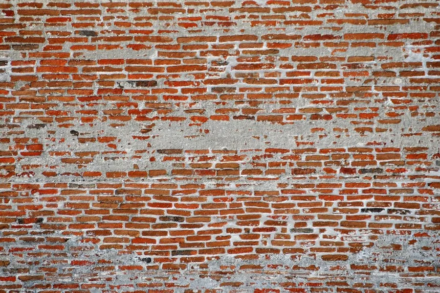 Aged red brick wall with peeling white paint and weathered texture