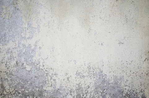Weathered concrete texture with peeling plaster in soft grey and cream tones