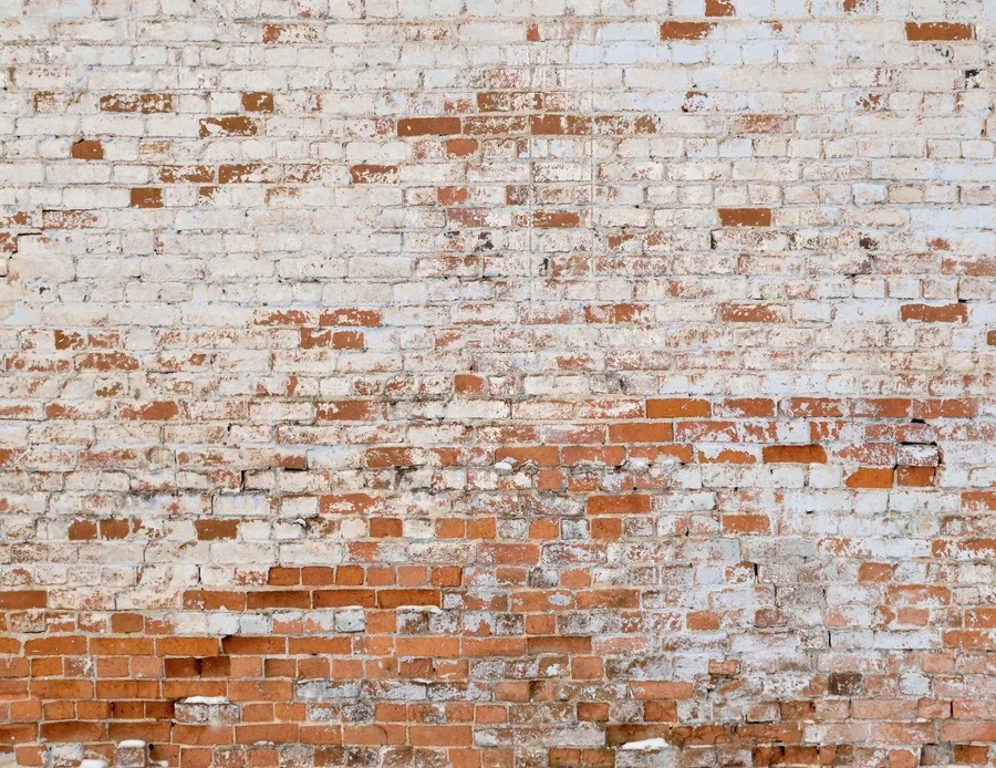 Distressed whitewashed brick wall texture with exposed red and cream bricks