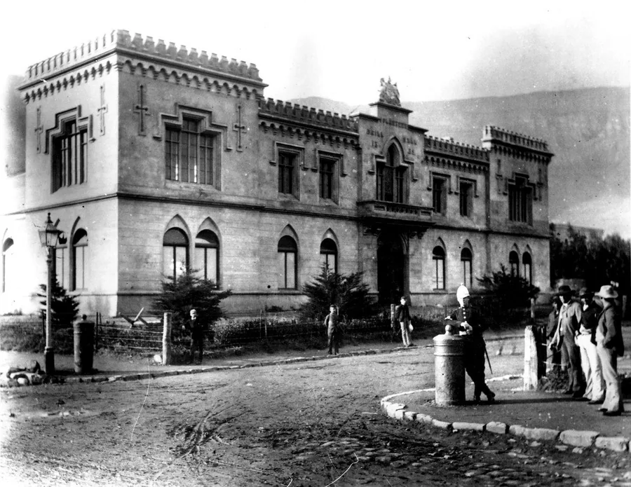 Historic stone mansion with crenellated towers, arched windows, and period architecture in monochrome.