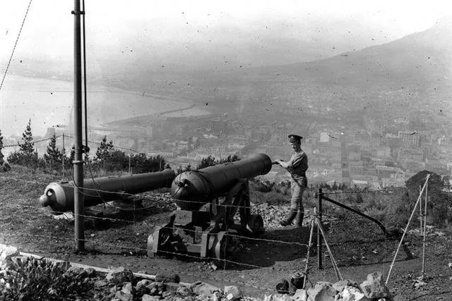 Vintage black and white photograph of an old cannon on a hillside overlooking a misty mountain valley city