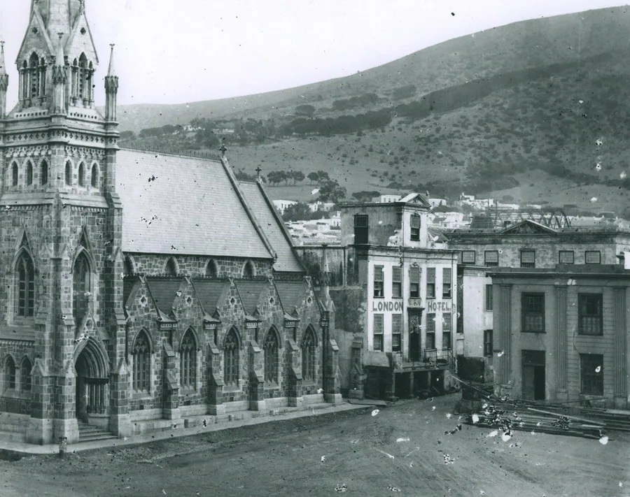 Black and white vintage photograph of Cape Town street with Gothic church, colonial buildings, and Table Mountain backdrop