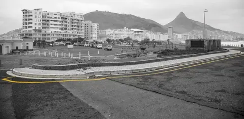 Black and white vintage photo of Cape Town with yellow road lines, mountains, and apartment buildings