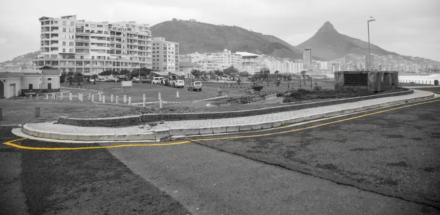 Black and white vintage photo of Cape Town with yellow road lines, mountains, and apartment buildings