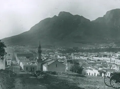 Vintage black and white photograph of Table Mountain overlooking Cape Town's white-washed buildings and church spire