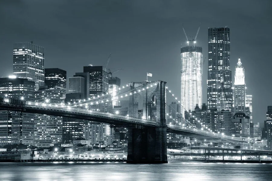 Night cityscape of Brooklyn Bridge and Manhattan skyline in black and white with glowing lights