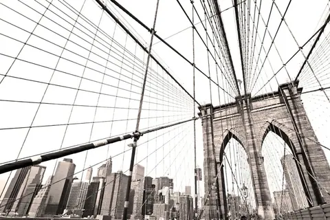 Brooklyn Bridge cables and NYC skyline viewed through architectural geometric perspective in black and white.