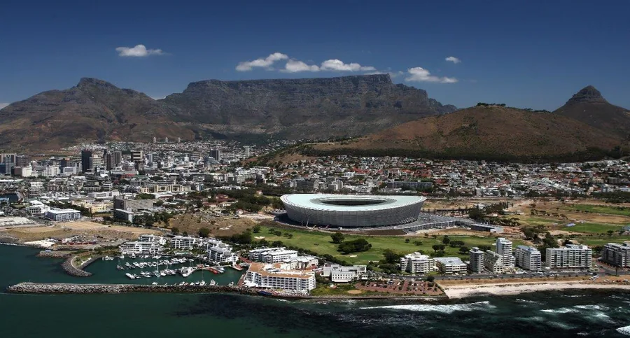 Aerial view of Cape Town with Table Mountain, stadium, and coastal city landscape under blue sky