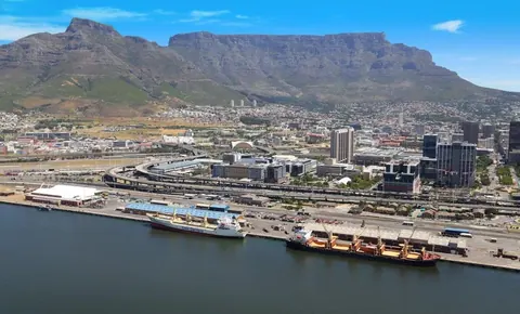 Aerial view of Cape Town city with Table Mountain, harbor, ships, and urban development under blue sky