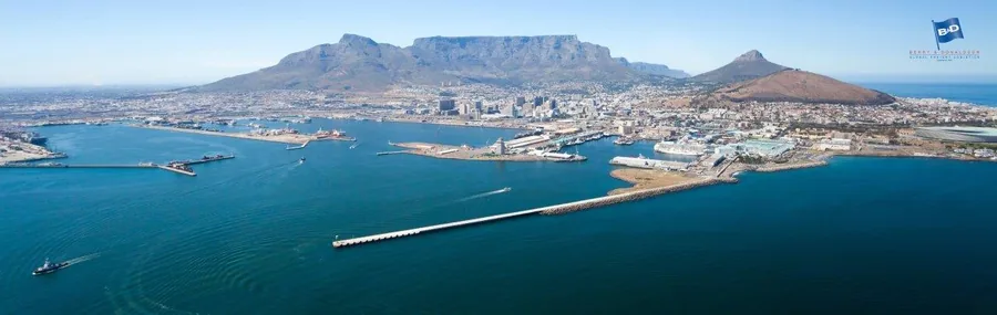 Aerial view of Cape Town with Table Mountain, blue ocean, harbor, and surrounding city landscape.