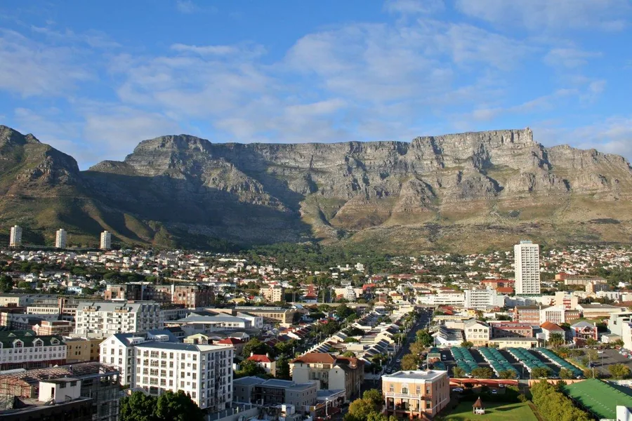 Aerial cityscape with colorful residential buildings and iconic flat-topped mountain backdrop under blue sky
