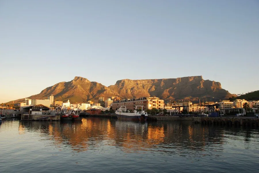 Table Mountain and Cape Town waterfront at sunset with buildings reflected in water