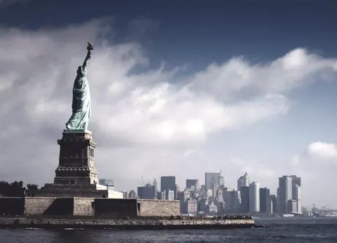 Statue of Liberty with Manhattan skyline and blue sky with white clouds