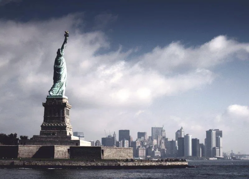 Statue of Liberty with Manhattan skyline and blue sky with white clouds