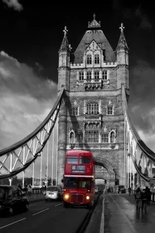 Black and white Tower Bridge with red London bus crossing the bridge against dramatic sky