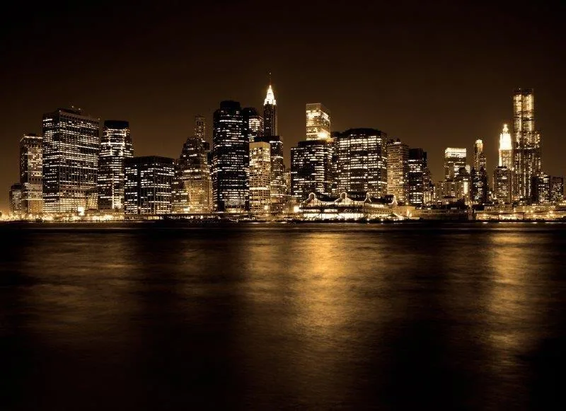 Night cityscape with glowing buildings and water reflection, golden and warm tones.