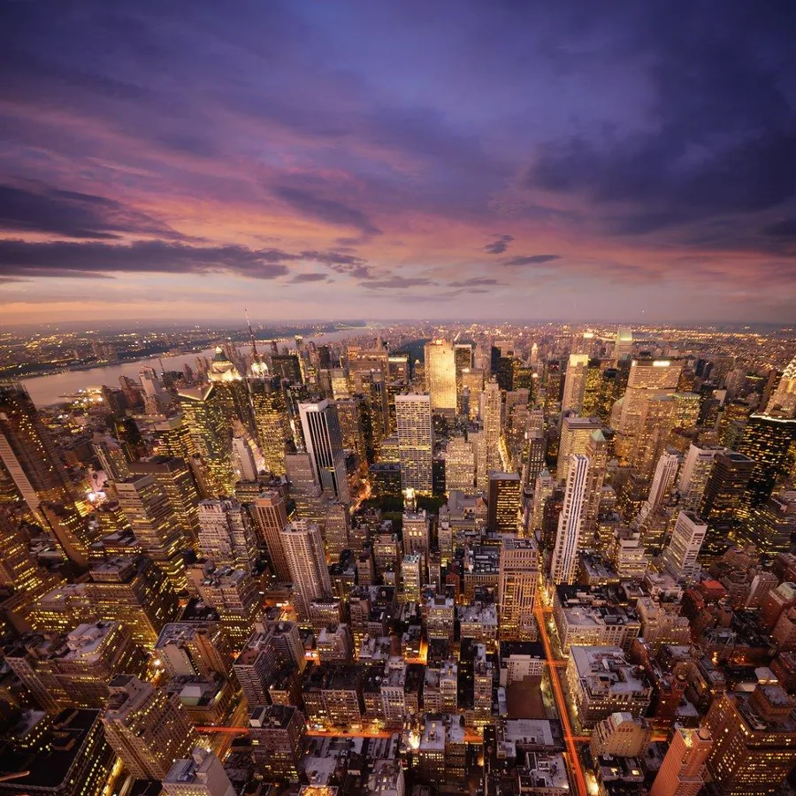 Aerial cityscape of Manhattan at sunset with illuminated skyscrapers and purple sky