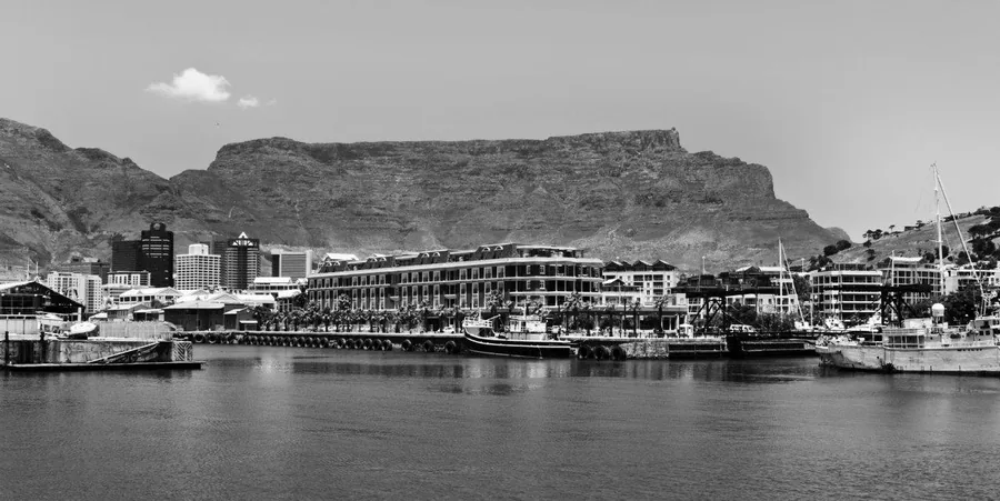 Black and white photograph of Cape Town harbour with Table Mountain backdrop and waterfront buildings