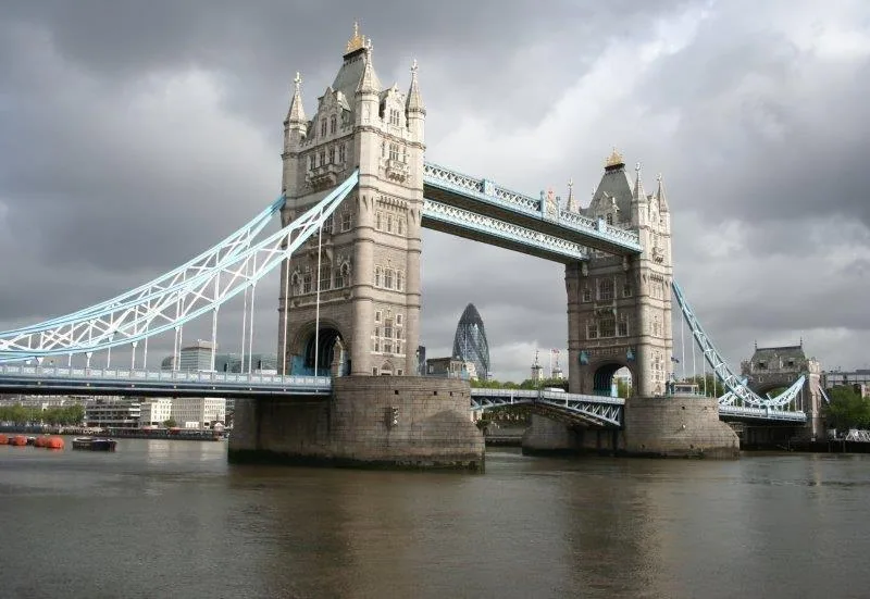 Tower Bridge London spanning the River Thames under cloudy skies with stone towers and steel suspension cables