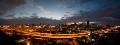 Night cityscape with golden-lit elevated highways and downtown skyline at dusk