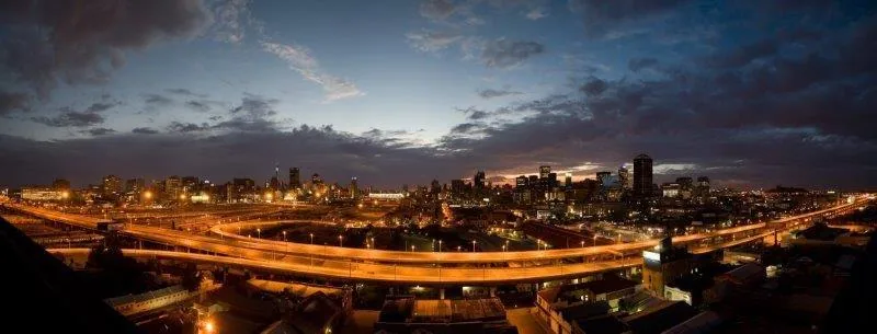Night cityscape with golden-lit elevated highways and downtown skyline at dusk