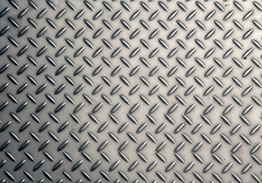 Repeating diamond plate metal texture pattern with embossed detail in metallic gray