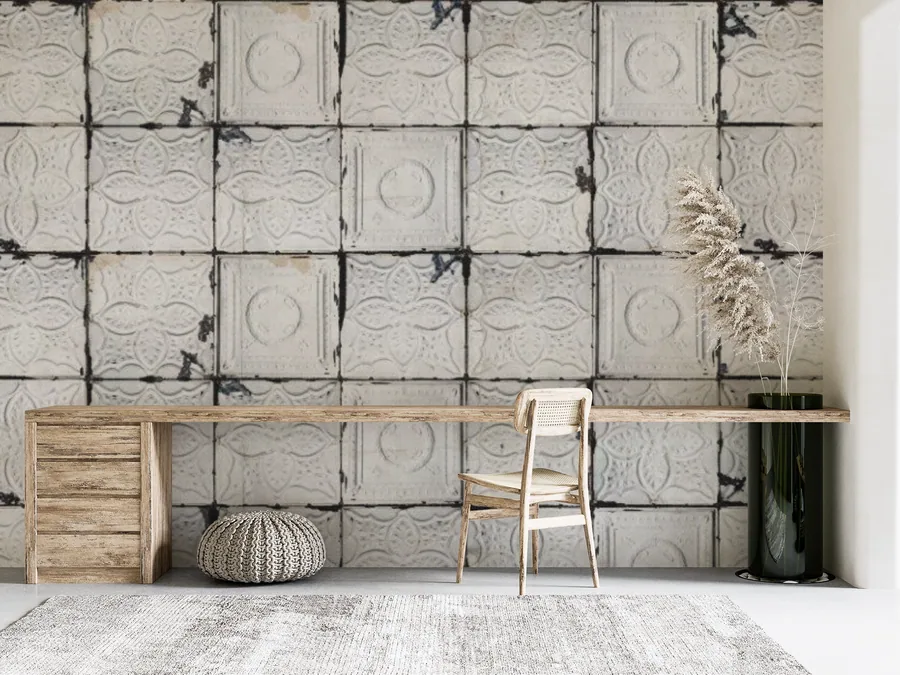 Beige concrete tile wall texture with embossed patterns and dark grout lines behind wooden desk setup