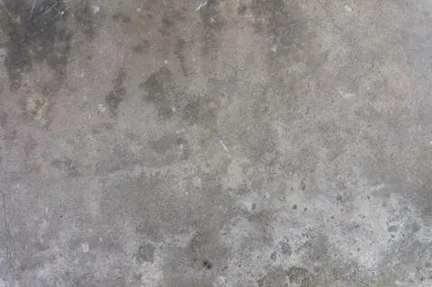 Close-up of weathered concrete surface with dust, stains, and natural texture variations