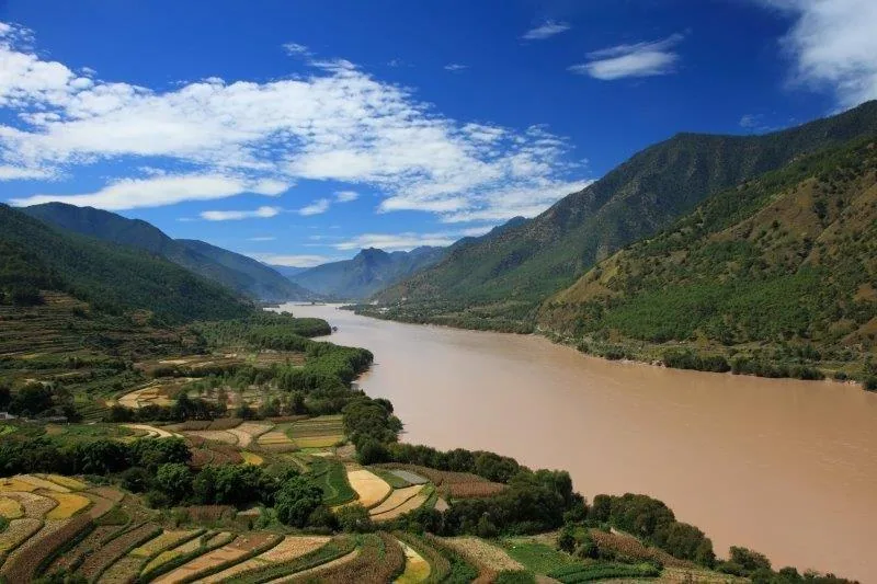 Aerial view of agricultural terraces along a misty river in a mountainous valley landscape