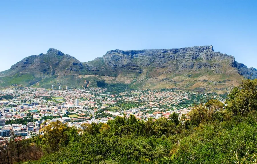 Aerial view of Table Mountain and Cape Town cityscape with green valleys and blue sky