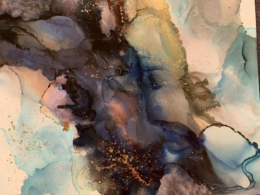 Abstract watercolor marble pattern with blue, gold, and cream swirls and speckled metallic accents