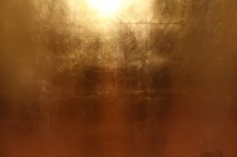 Warm bronze metallic texture with grid pattern and golden light reflections