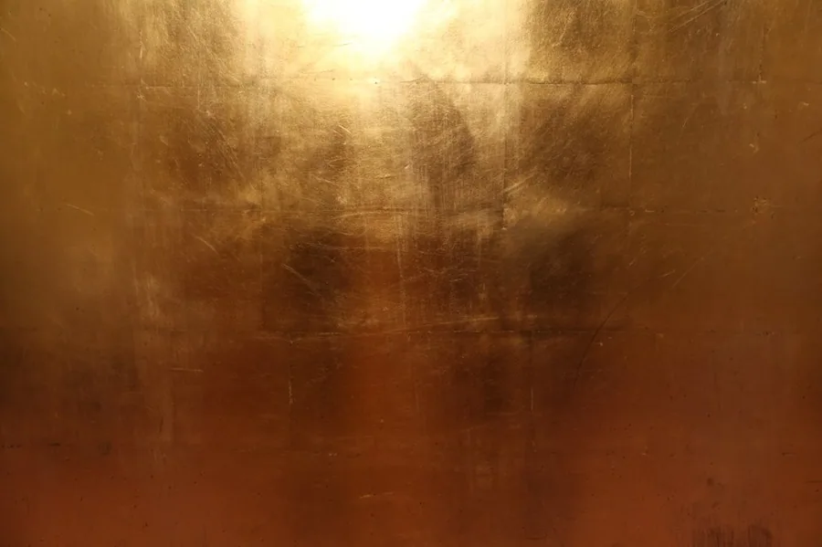 Warm bronze metallic texture with grid pattern and golden light reflections