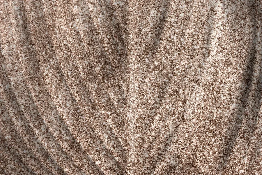 Close-up of speckled metallic wallpaper texture in taupe and cream with vertical wave pattern