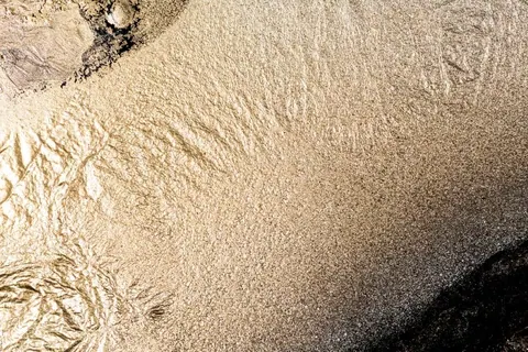 Metallic gold and bronze wallpaper with flowing, organic molten-effect patterns and gradual tonal transitions.
