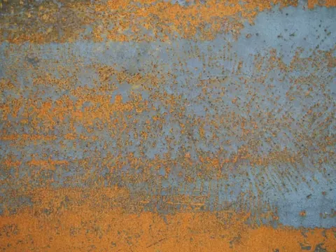Weathered metal surface with orange rust patina and blue-grey oxidation texture