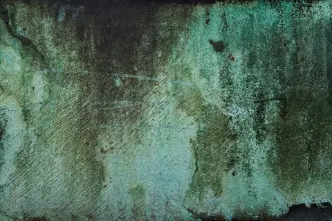 Weathered metal surface with green patina, rust stains, and textured oxidation marks.