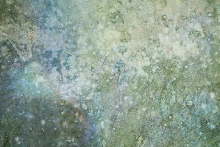Weathered metal surface with green and blue patina, rust spots, and oxidized texture