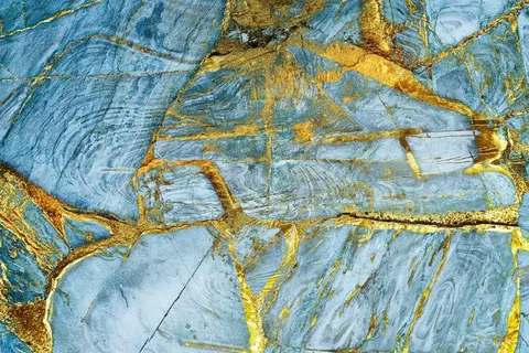 Blue slate texture with golden metallic cracks and veins, resembling oxidized metal or cracked stone.