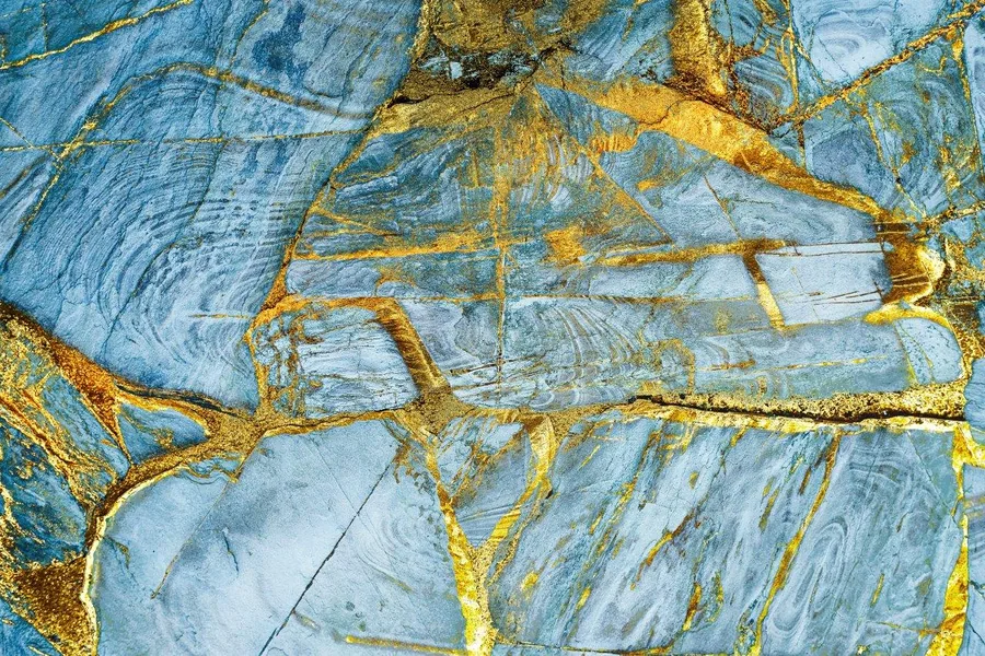Blue slate texture with golden metallic cracks and veins, resembling oxidized metal or cracked stone.