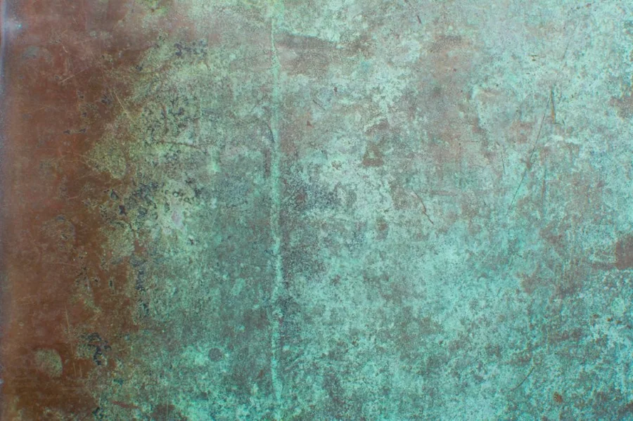 Aged metal surface with verdigris patina, rust and turquoise oxidation texture.