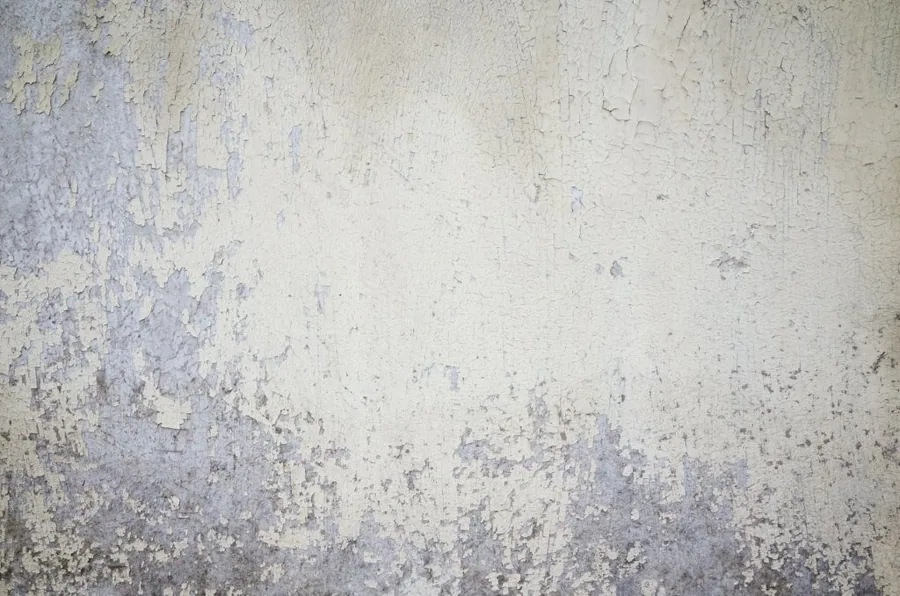 Weathered concrete wall with peeling paint and distressed texture in neutral tones